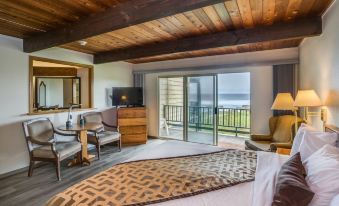 a spacious bedroom with a large bed , a chair , and a view of the ocean at Adobe Resort