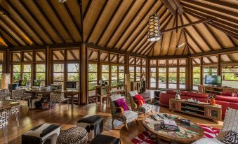 a spacious living room with wooden furniture , including a couch , chairs , and a coffee table at Four Seasons Resort Maldives at Kuda Huraa