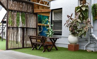 a wooden bench is sitting in front of a white house with green grass on the ground at Hobart Tower Motel