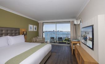 a hotel room with a large bed , a television , and a balcony overlooking the ocean at Sea World Resort