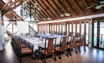 a large dining room with a long table set for a formal event , complete with chairs , flowers , and a chandelier at Anantara Dhigu Maldives Resort