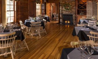 a large dining room with wooden floors , tables covered in black and white checkered tablecloths , and a fireplace at Glen-Ella Springs Inn