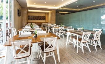 a large dining room with white tables and chairs arranged for a group of people to enjoy a meal together at Novena Hotel Bandung