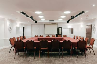 a large conference room with a round table surrounded by chairs and a projector screen at Best Western Bradford Guide Post Hotel Best Western Bradford Guide Post Hotel Photo