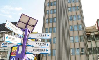 a tall building with a blue and white sign on top , surrounded by other buildings and people at Airline Inn Kaohsiung Station