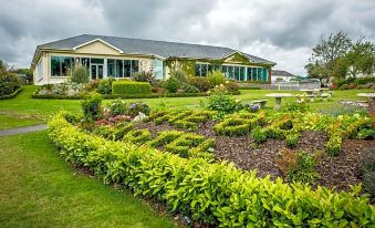 a large house with a well - maintained garden in front of it , surrounded by various plants and flowers at Arklow Bay Hotel