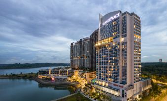 a large hotel with a blue and white sign is situated next to a body of water at Fraser Place Puteri Harbour, Johor