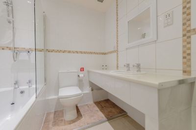 a modern bathroom with white walls , wooden floor , and a toilet with a bidet function at Best Western Bradford Guide Post Hotel Best Western Bradford Guide Post Hotel Photo