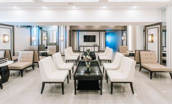 a modern living room with white couches , chairs , and a black coffee table , surrounded by large windows at Rizal Park Hotel