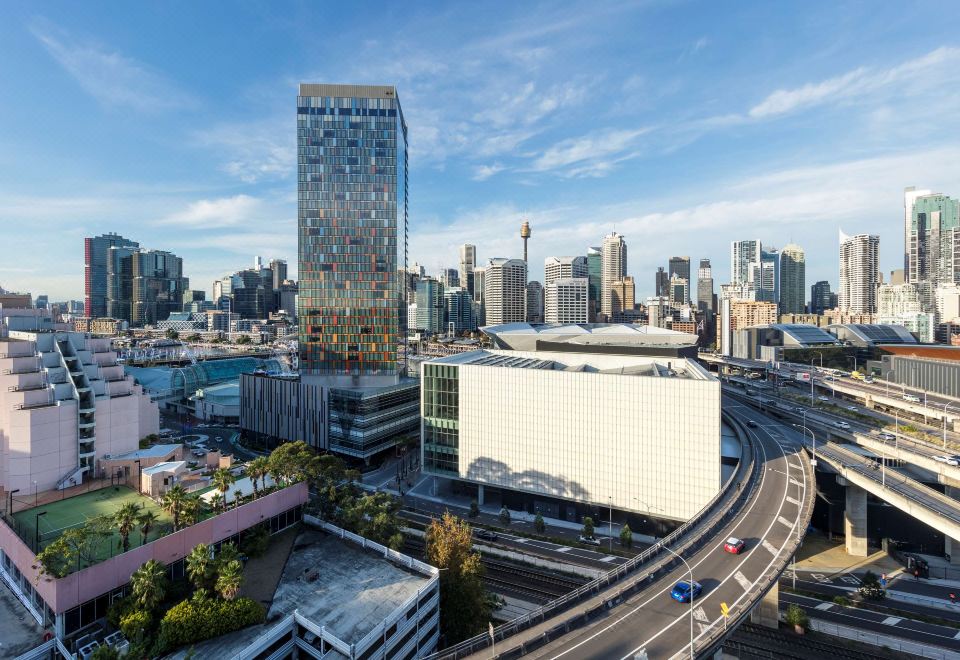 a cityscape with a tall building in the center and other buildings surrounding it , including a white building on the left at Oaks Sydney Goldsbrough Suites