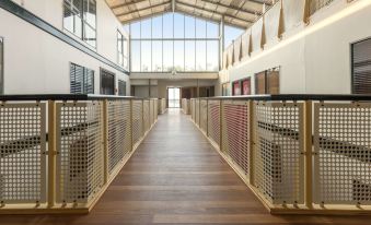 a long , empty hallway with wooden flooring and metal railings , leading to a large open space with windows at Oaks Sydney Goldsbrough Suites