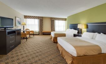 a hotel room with two beds , a tv , and chairs , all neatly arranged on the carpeted floor at Holiday Inn Statesboro-University Area