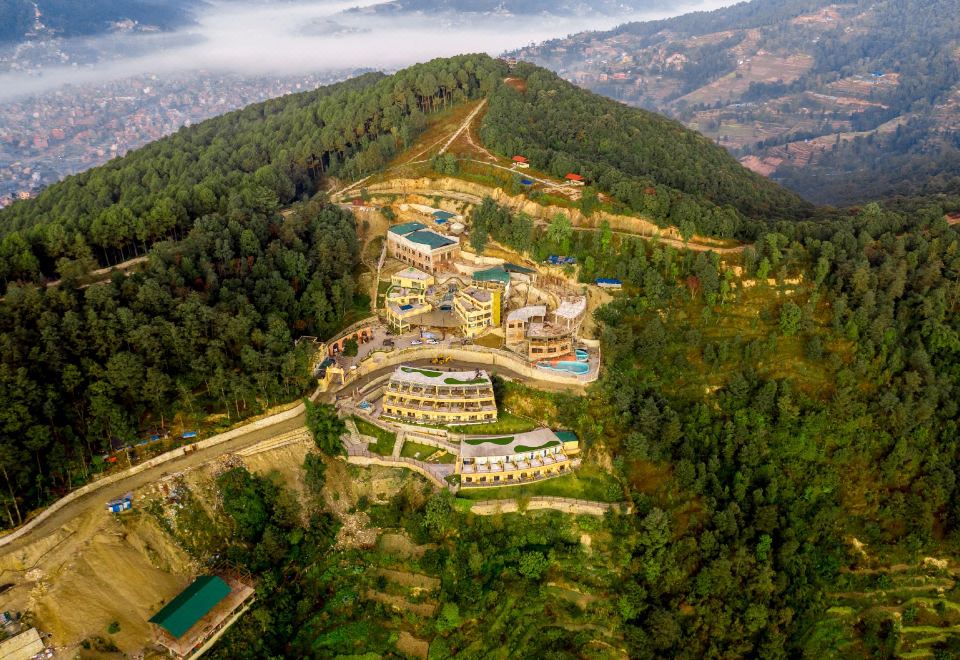 a bird 's eye view of a mountainous area with buildings and roads , surrounded by trees at Aagantuk Resort