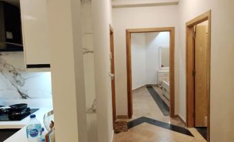 a hallway with white walls , a checkered floor , and a mirror on the wall , leading to a bathroom at Parkway Apartments