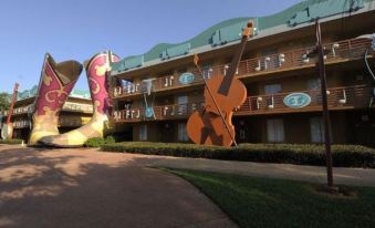 a building with a large teddy bear statue on the left and two large brown and black instruments on the right at Disney's All-Star Music Resort