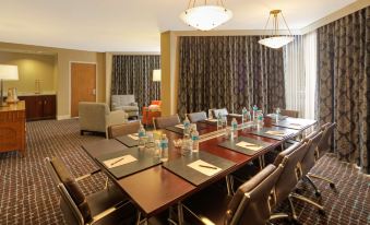 a conference room with a long table , chairs , and water bottles set up for a meeting at Hilton Houston Westchase