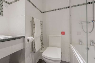 a white toilet and sink in a bathroom with a roll of toilet paper on the wall at Best Western Bradford Guide Post Hotel Best Western Bradford Guide Post Hotel Photo