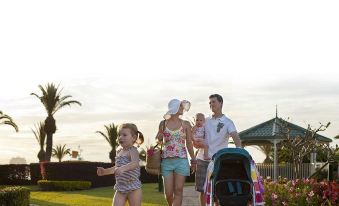 a family of four , including a man , woman , and two children , are walking down a path near a grassy area at Sea World Resort