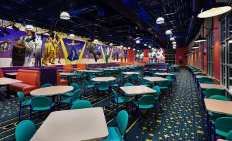 a large dining room with multiple tables and chairs , as well as a stage with performers on it at Disney's All-Star Music Resort