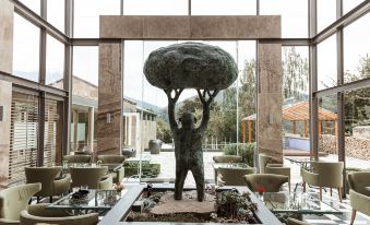 a statue of a person holding a tree is displayed in the middle of a room with large windows at Islington Hotel