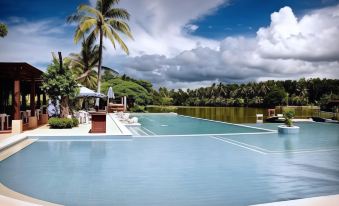 a large outdoor swimming pool surrounded by lush greenery and palm trees , creating a serene and inviting atmosphere at San Antonio Resort