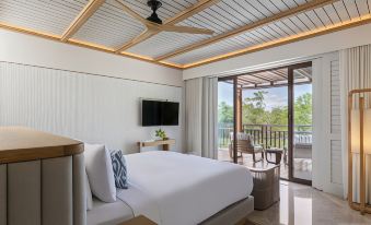 a large , white bed is in a room with a sliding glass door leading to an outdoor patio at Fairmont Mayakoba