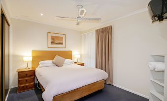 a bedroom with a large bed , wooden headboard , and a ceiling fan in the room at Parkwood Motel & Apartments