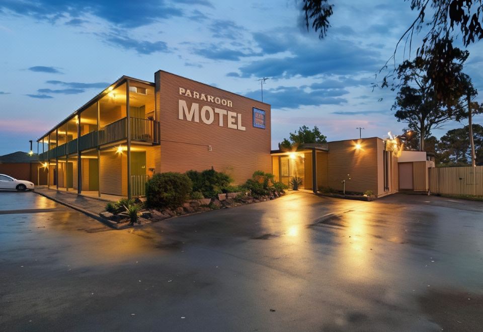 "a large , two - story motel with a sign that reads "" parmacell motel "" is surrounded by trees and parked cars" at Parkwood Motel & Apartments