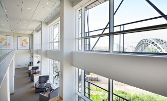 a modern office building with large windows and metal bars on the upper floors , allowing natural light to fill the space at Hilton Newcastle Gateshead