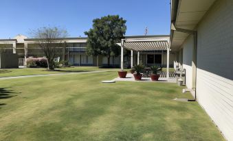 a large , well - maintained lawn with multiple potted plants and a covered patio area in front of a building at Ramada by Wyndham New Iberia