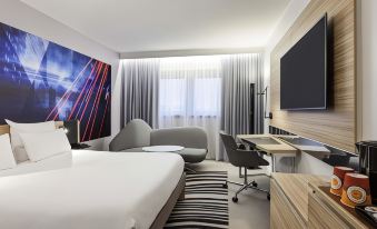 a modern hotel room with a large bed , white walls , and a flat - screen tv on the wall at Novotel Tours Centre Gare