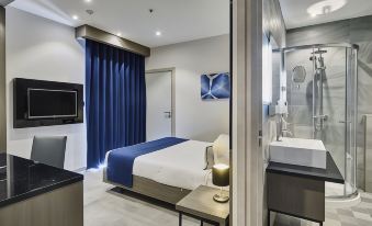 a modern hotel room with a blue and white color scheme , featuring a bed , a tv , and a bathroom at The District Hotel