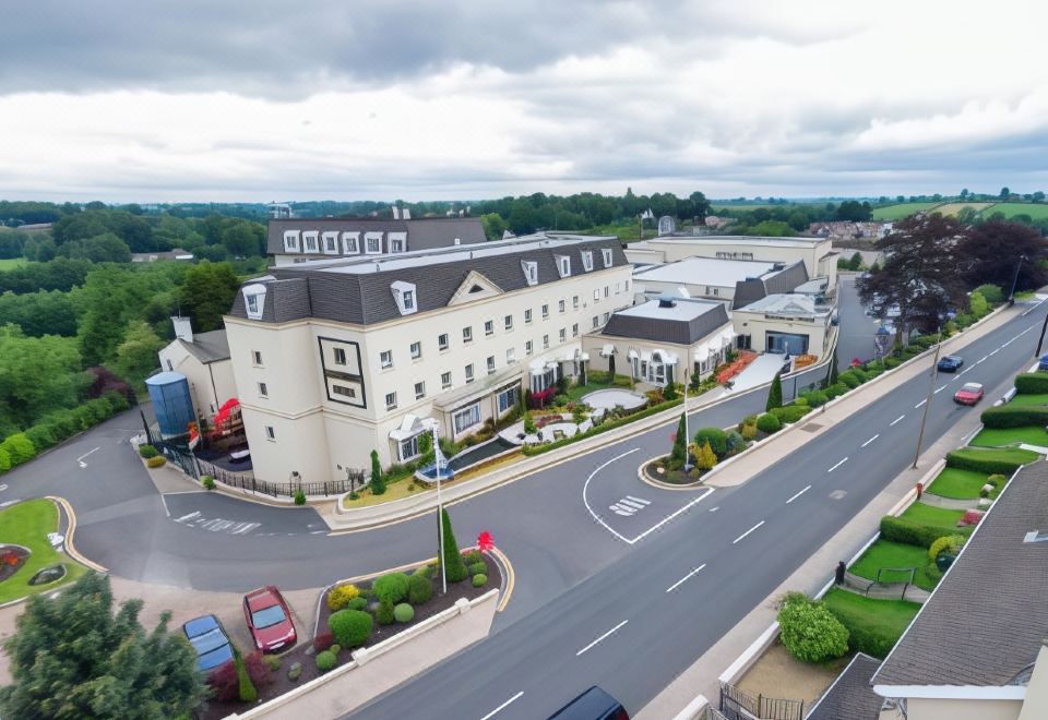 a large hotel with multiple buildings and a parking lot , surrounded by cars and trees at Hillgrove Hotel, Leisure & Spa