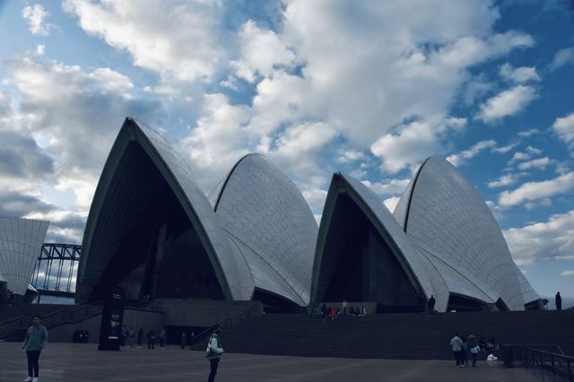 Sydney Opera House, Harbour Bridge, and clouds.