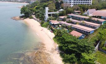 aerial view of a sandy beach with a building in the background , surrounded by trees at Pattaya Paradise Beach Resort