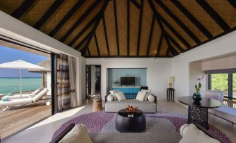 a spacious living room with a high ceiling , large windows , and a fireplace is shown at Four Seasons Resort Maldives at Kuda Huraa