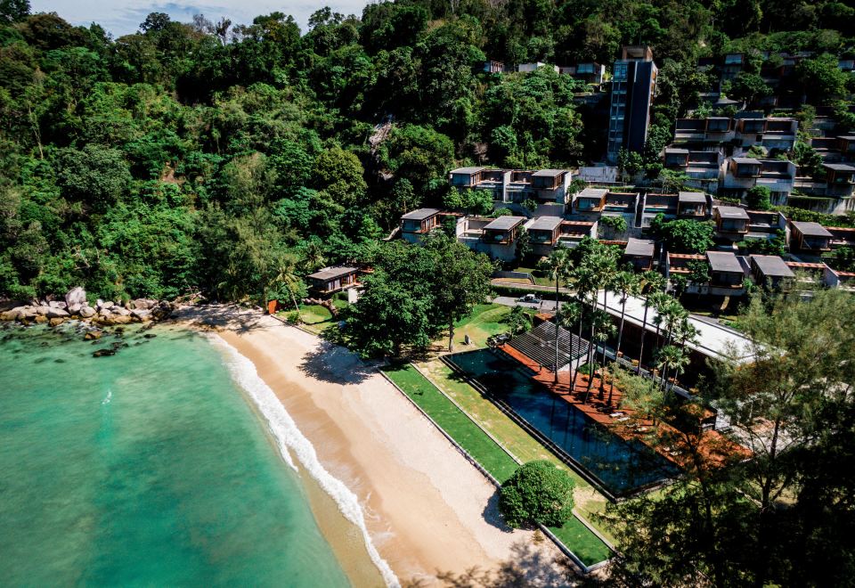 aerial view of a tropical resort surrounded by lush greenery , with a beach visible in the background at The Naka Phuket, a member of Design Hotels