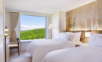 a hotel room with two beds , one on each side of the room , and a view of the mountains outside the window at The Westin Rusutsu Resort