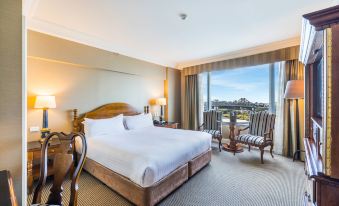 a hotel room with a king - sized bed , two chairs , and a window overlooking the city at Stamford Plaza Brisbane