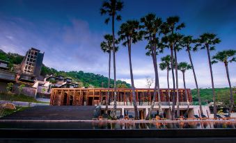 a modern building with palm trees and a large pool is shown in the image at The Naka Phuket, a member of Design Hotels