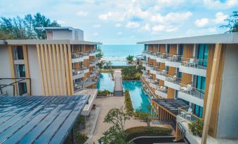 a large resort with multiple buildings , a swimming pool , and a view of the ocean at Sand Dunes Chaolao Beach Resort