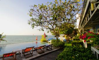 a resort with a pool surrounded by lounge chairs and umbrellas , as well as a view of the ocean at Pattaya Paradise Beach Resort