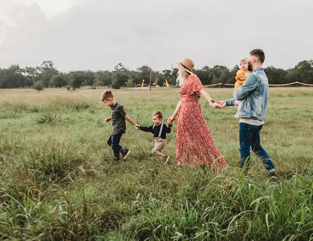 2 parents and 3 children walking through a field