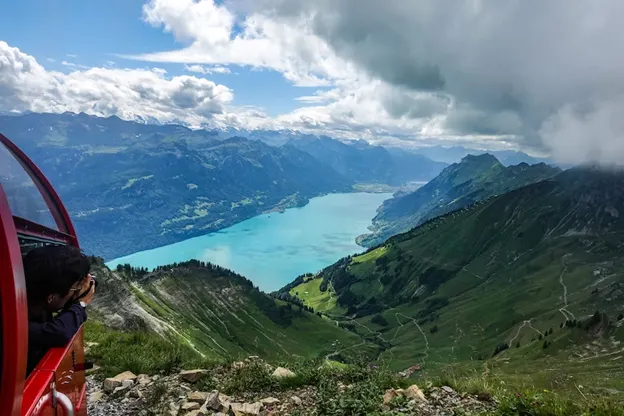 A person taking a picture out the window on the Brienz Rothorn Bahn