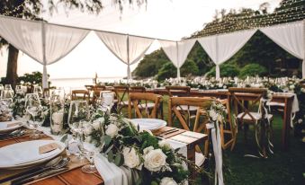 a wedding reception on the beach , with tables set up for guests and decorated with flowers at The Naka Phuket, a member of Design Hotels