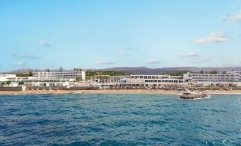 a large hotel situated on the beach , with clear blue water and a beautiful view of the ocean at Grecotel LUXME White