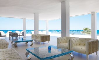 a large , modern living room with multiple couches and chairs , all facing the ocean at Grecotel LUXME White