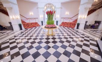 a large , white - tiled room with black and white checkered floors and a chandelier hanging from the ceiling at Rizal Park Hotel