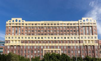 a large red brick building with gold lettering on the side and a blue sky in the background at Oaks Sydney Goldsbrough Suites