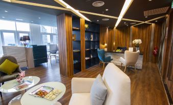 a modern living room with wooden walls , a white couch , and various seating options , including a dining table and chairs at Fraser Place Puteri Harbour, Johor